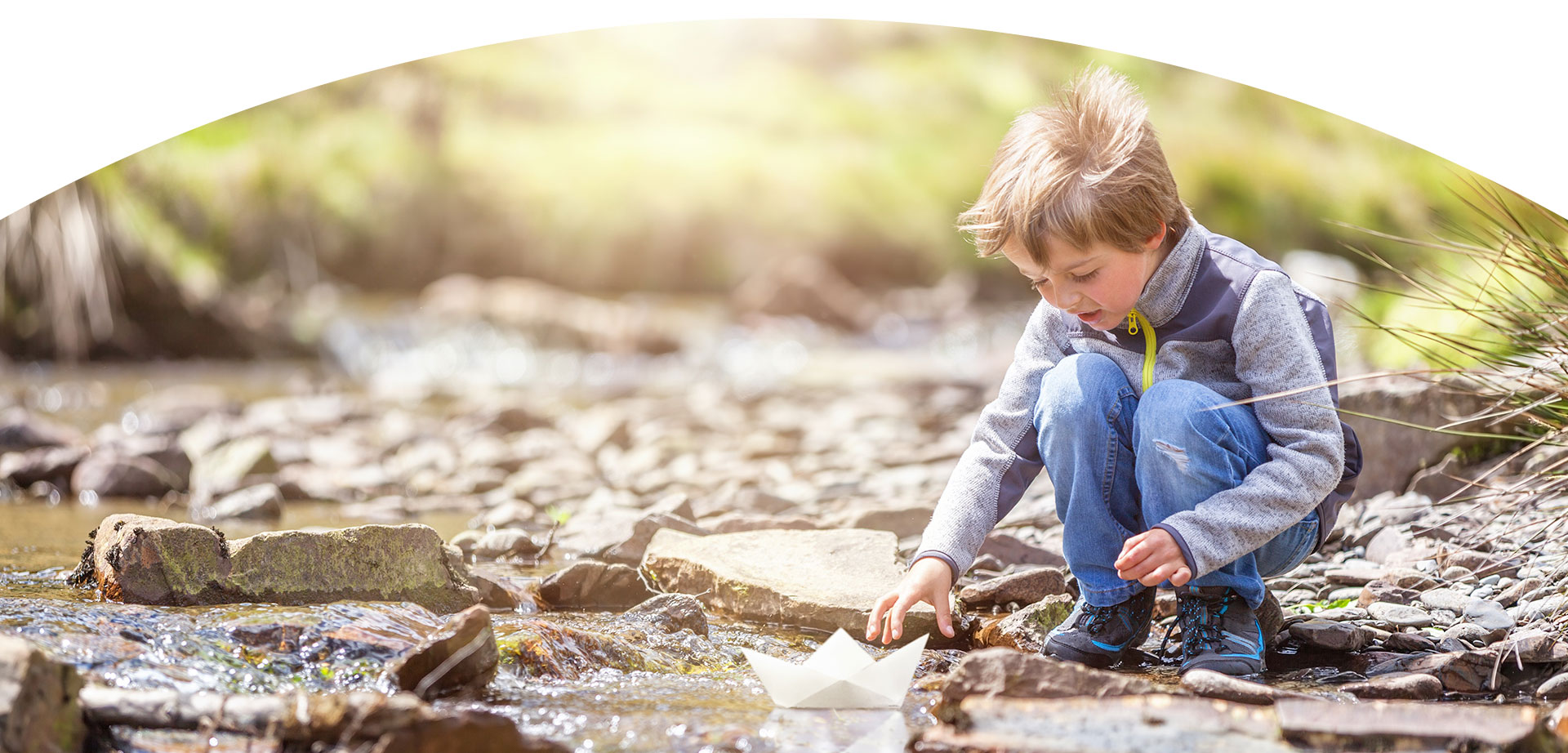 Boy sailing a paper boat in the creek